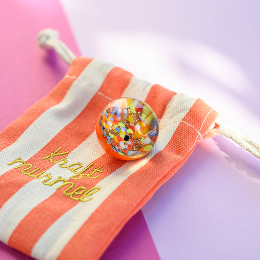 Kraftmurmel aus Muranoglas (orange mit Konfetti-Steinchen) 25mm, in hochwertigem Stoffbeutel mit Stickerei