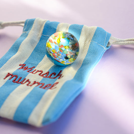 Kraftmurmel aus Muranoglas (blau mit Konfetti-Steinchen) 25mm, in hochwertigem Stoffbeutel mit Stickerei
