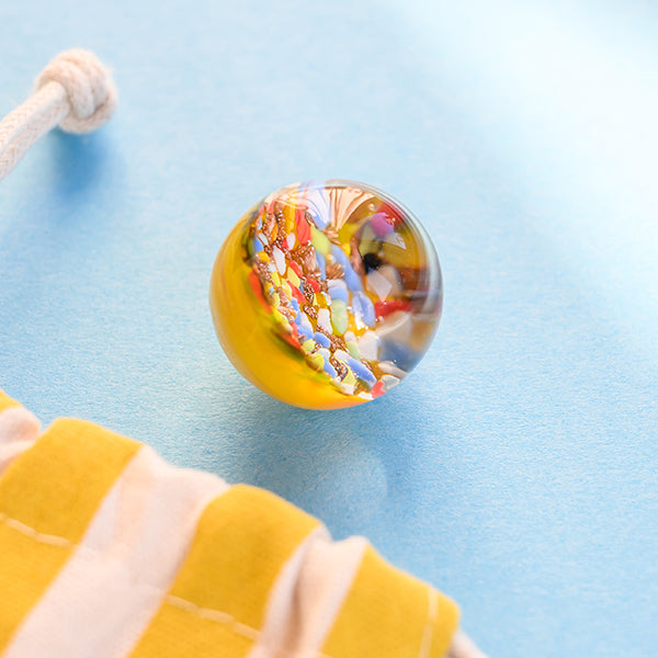 Kraftmurmel aus Muranoglas (gelb mit Konfetti-Steinchen) 25mm, in hochwertigem Stoffbeutel mit Stickerei